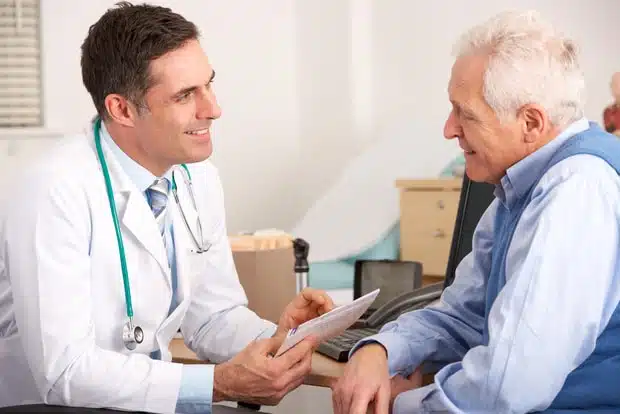 Un médico reunido con un paciente anciano en una sala de examen.