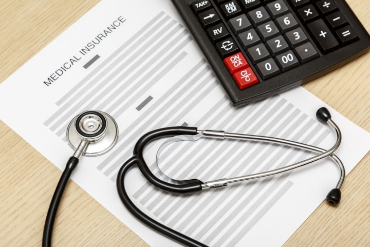 A stethoscope and an open enrollment medical insurance form.