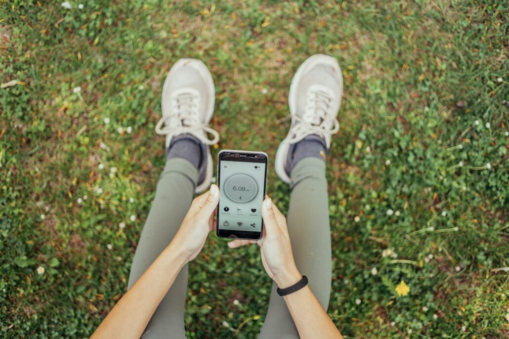 view from above of unrecognizable indian woman usinig running app sitting in park