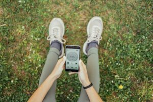 view from above of unrecognizable indian woman usinig running app sitting in park