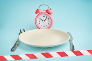 Alarm clock, plate and barrier tape. intermittent fasting, lunchtime, diet and weight loss