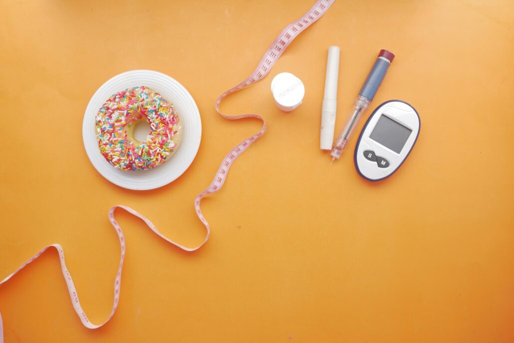 diabetic measurement tools, insulin and donuts on pink