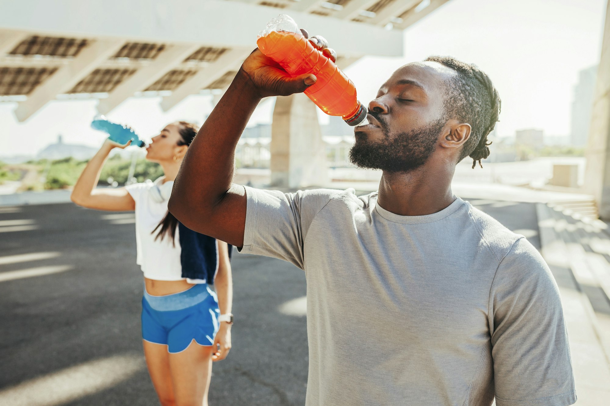 Sporty runners couple drinking energy drink after running