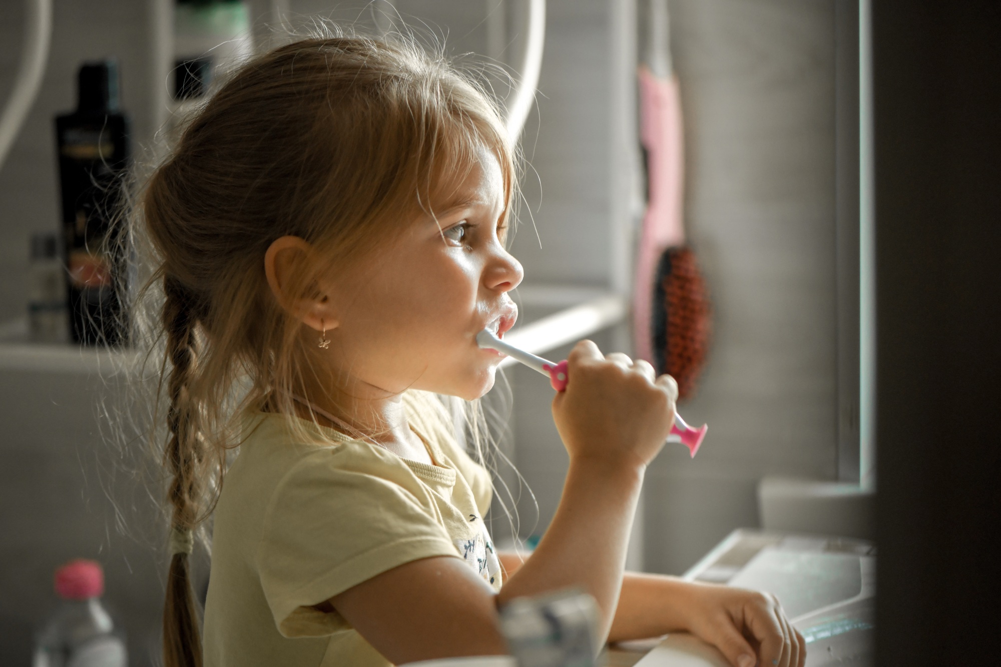 A little girl washes herself and brushes her teeth at home in the morning