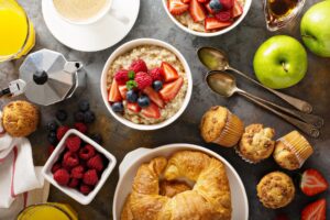 Breakfast table with oatmeal porridge, croissants and muffins