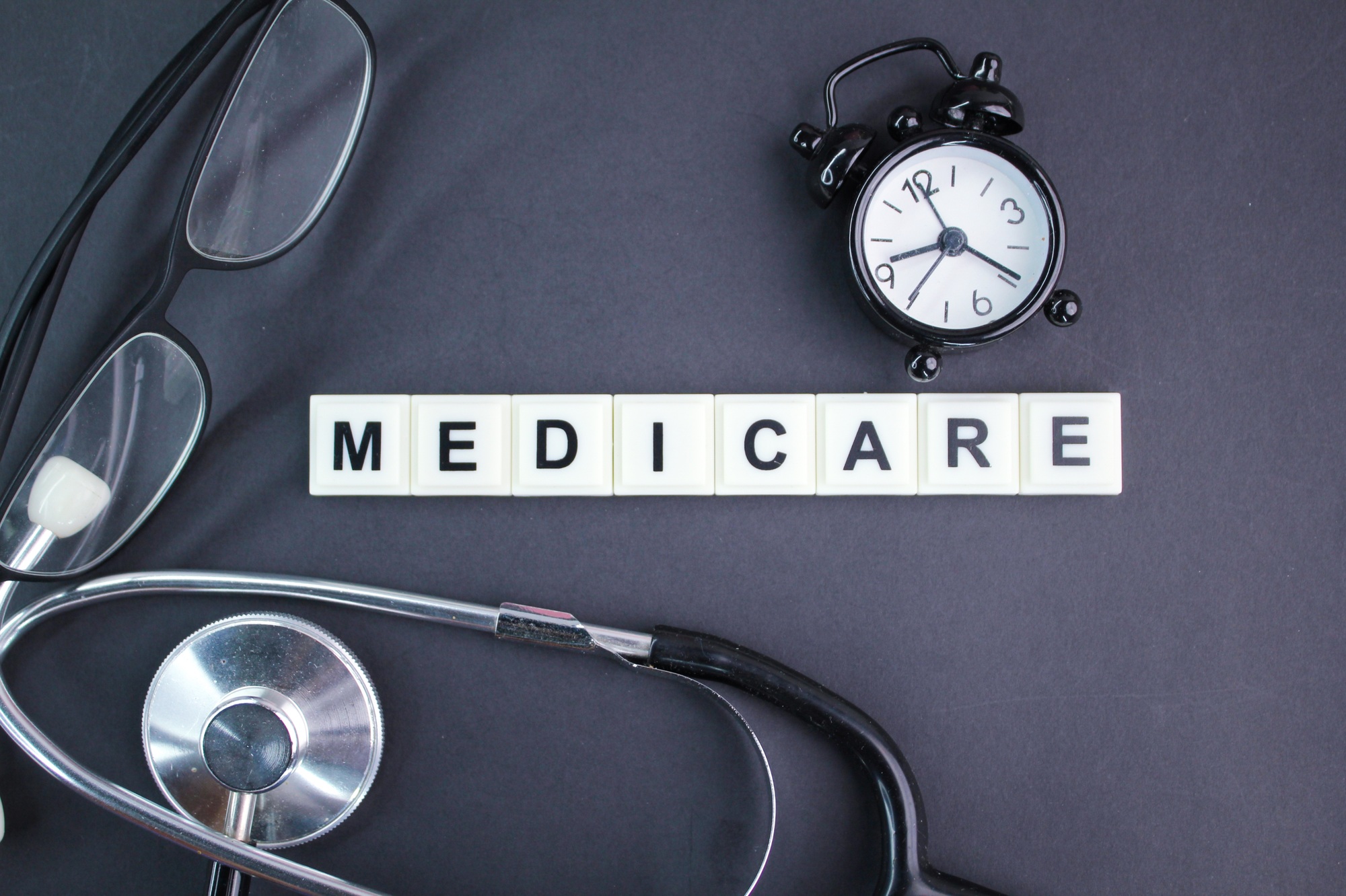 stethoscope, glasses, alarm clock with the alphabet word medicare.