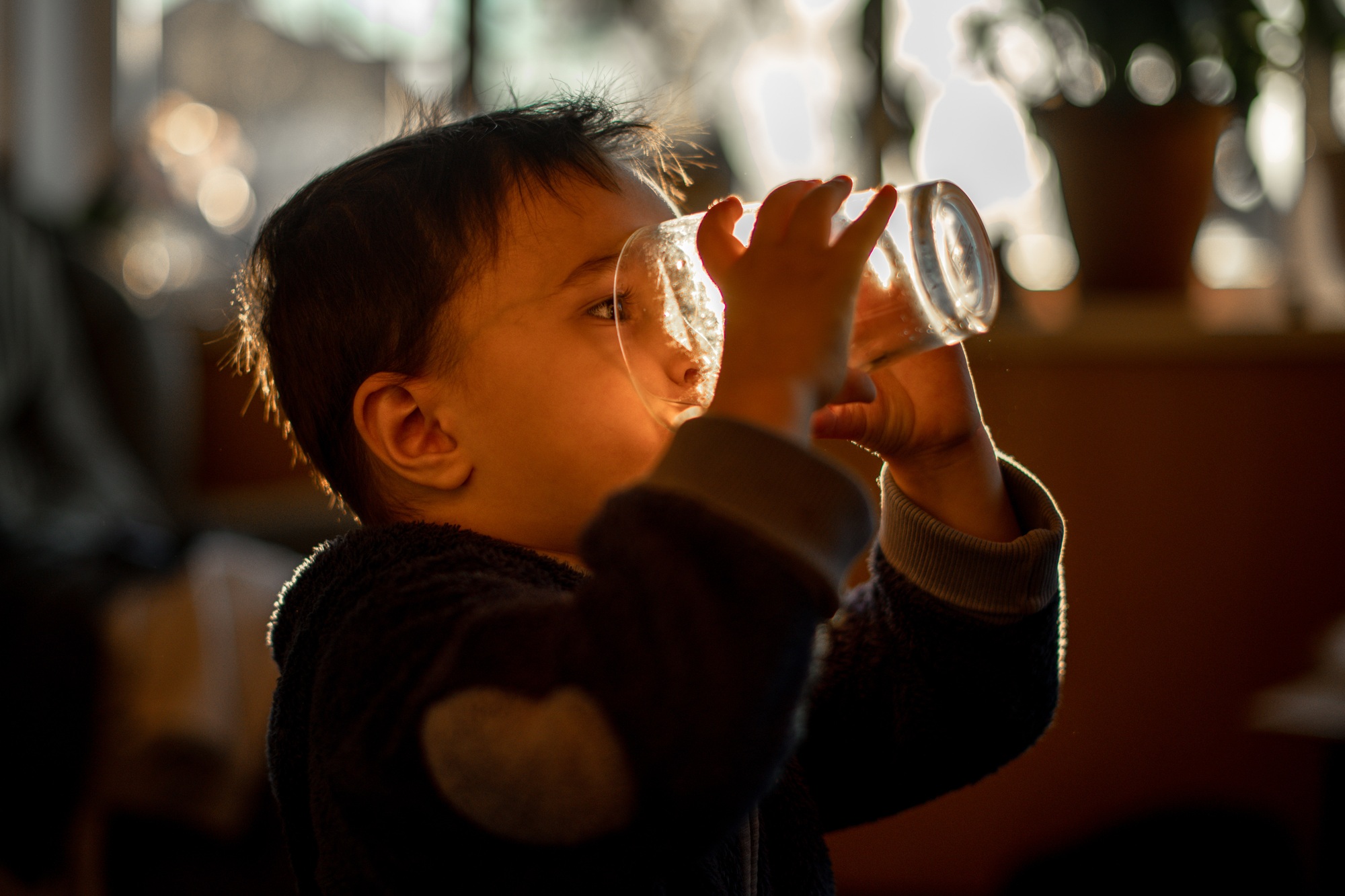 The child drinks water from a glass