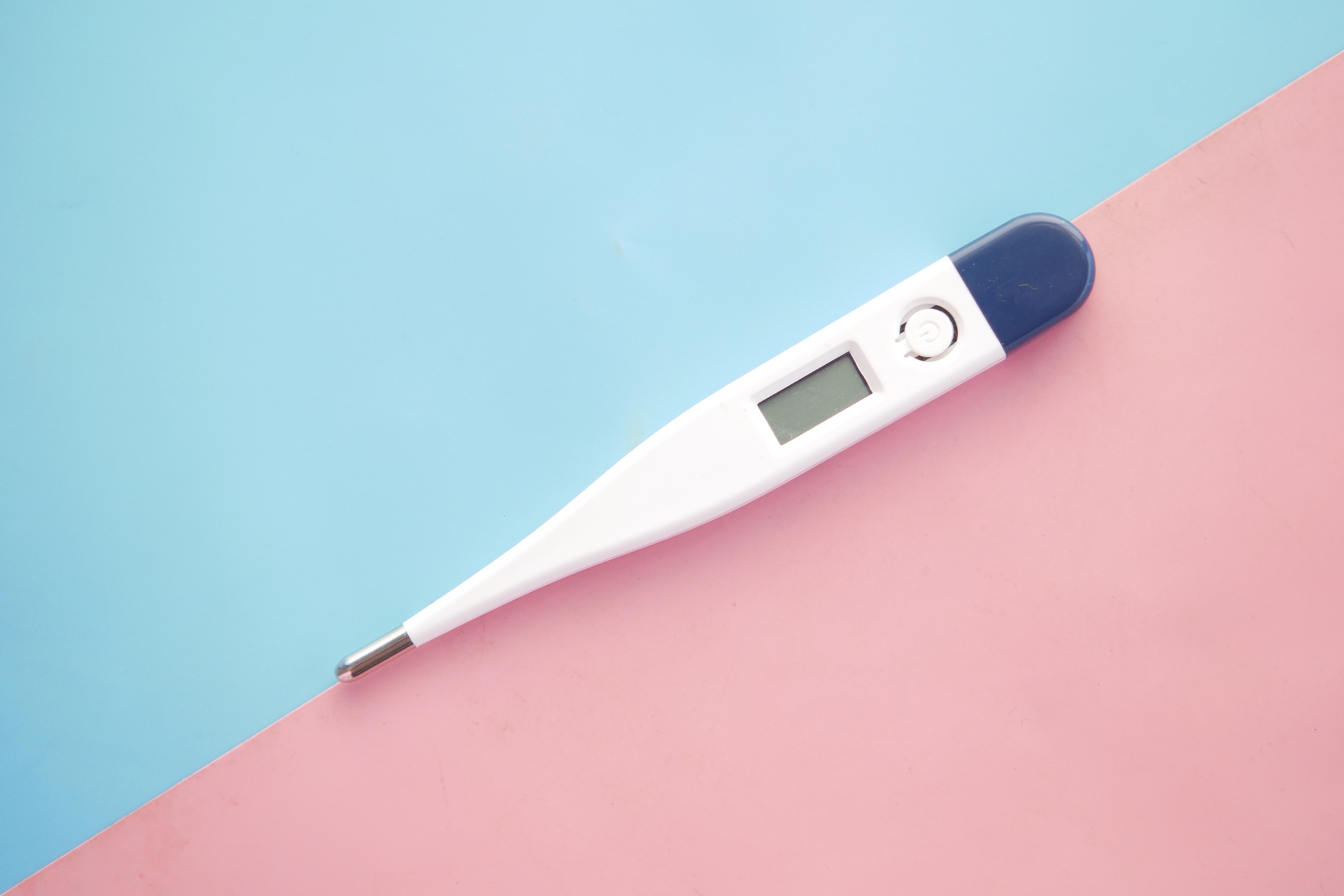 digital thermometer on pink background with copy space