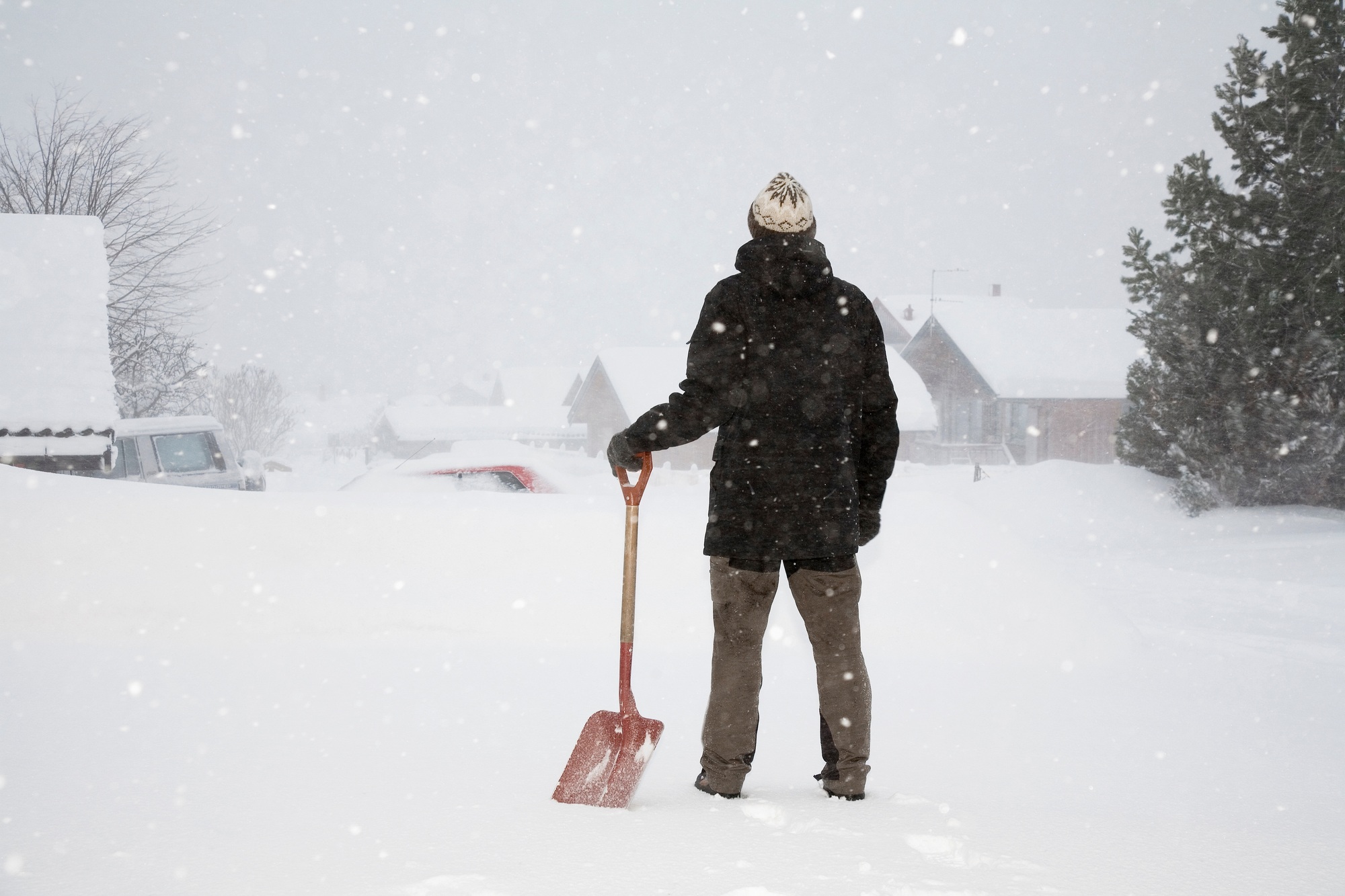 Man standing in snow with shovel