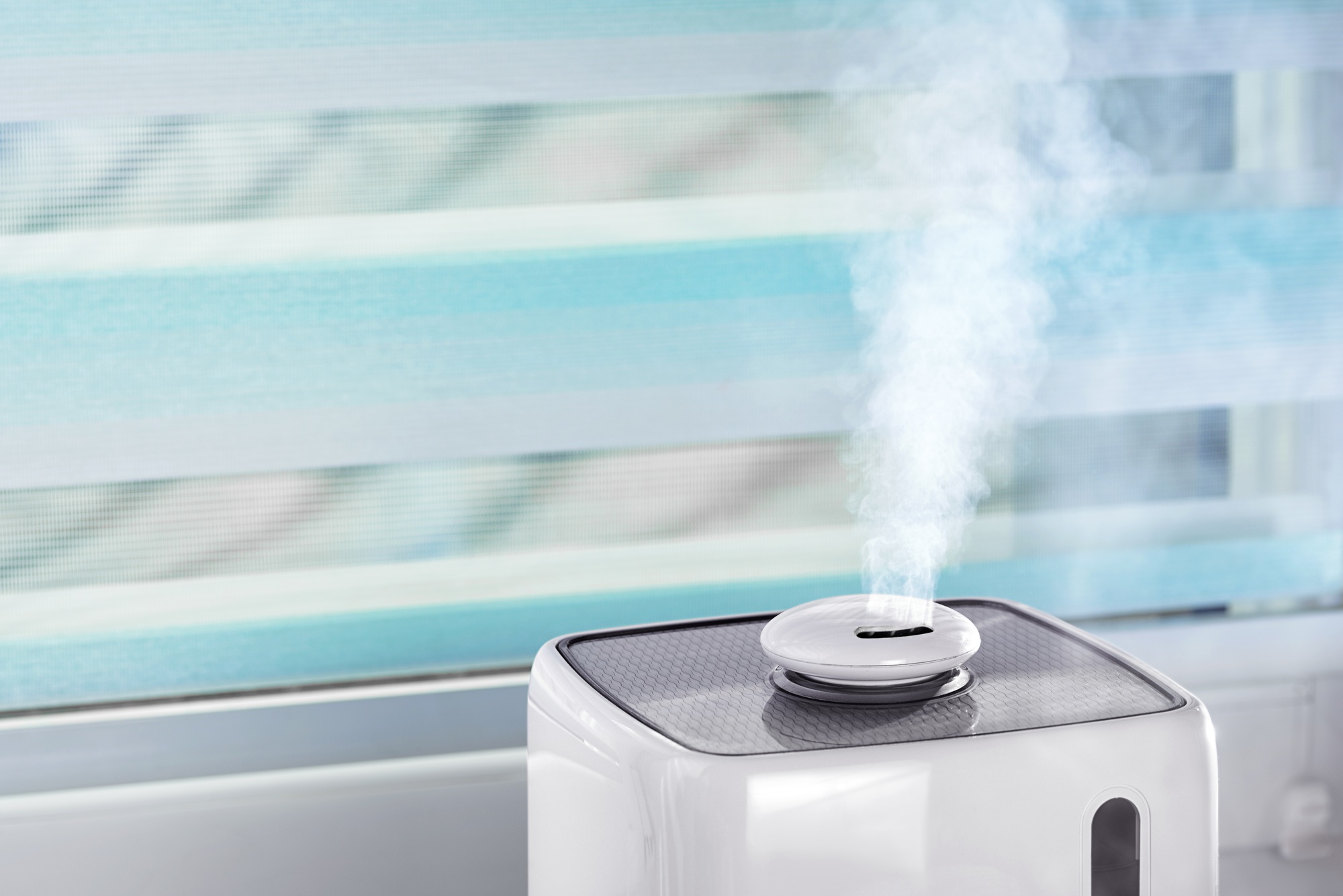 The white ultrasonic humidifier on a window moistens dry air